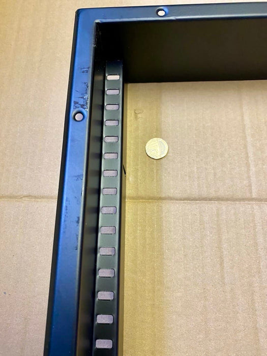 A close-up of a black metal frame photographed on a brown cardboard surface with a coin nearby for scale.