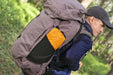 Bestway RidgeLite Large Insulated Mummy Sleeping Pad Person wearing a large backpack with a visible orange pocket, walking outdoors.