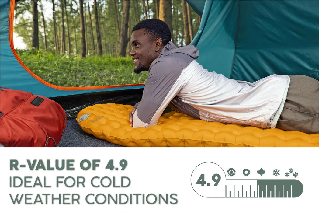 Bestway RidgeLite Insulated Regular Mummy Sleeping Pad  Person lying on a camping mattress with a tent in the background, highlighting R-value of 4.9 for cold weather.