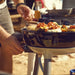 Cadac Carri Chef 40 QR BBQ, Paella Pan & Grill Combo - lifestyle image, showing BBQ being used to cook food
