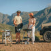 Cadac Carri Chef 40 QR BBQ, Paella Pan & Grill Combo - lifestyle image, showing couple using BBQ to cook food