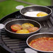 Cadac Tapas Dishes - Set of 4 - lifestyle image, showing three tapas dishes being used to cook egg, tomatoes, and beans on camping barbecue