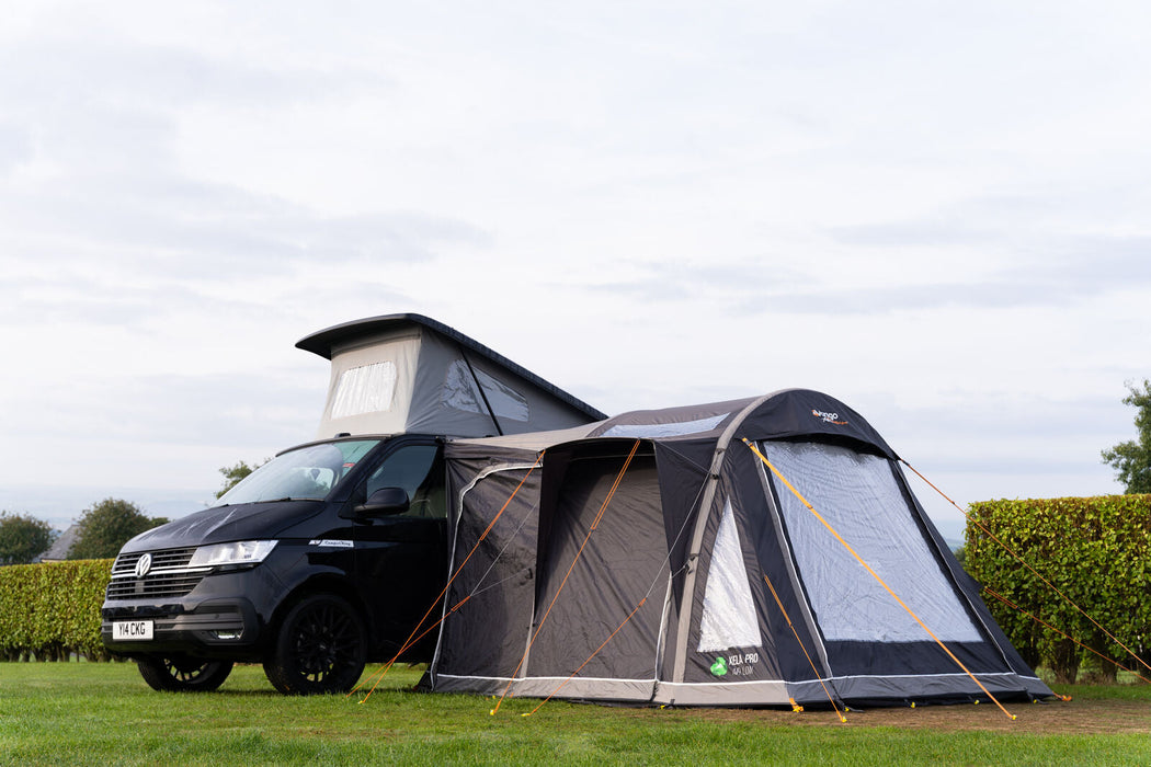 Vango Kela Pro Air Drive Away Awning - Low lifestyle image of awning pitched on VW camper wit pop top on campsite. Side view showing left side with all doors zipped up and privacy curtains. 
