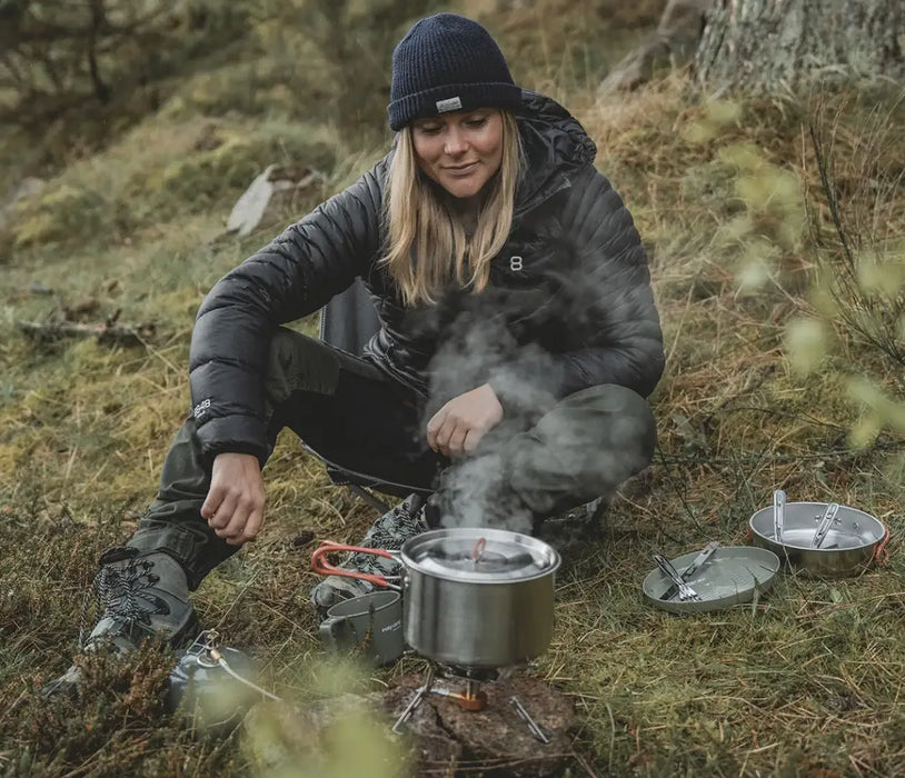 Easy Camp Moss 4 Person Camping Cook Set - product image, showing person using pot on top of camping stove, with mug, plate, and pan
