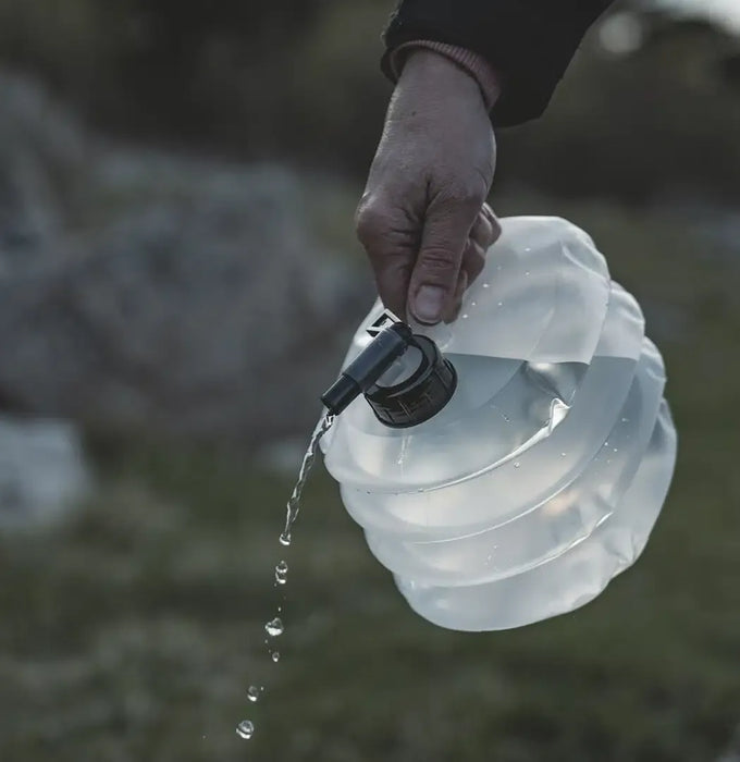 Easy Camp Nettle Folding 3 Litre Camping Water Carrier - lifestyle image, showing person pouring water out of carrier tap