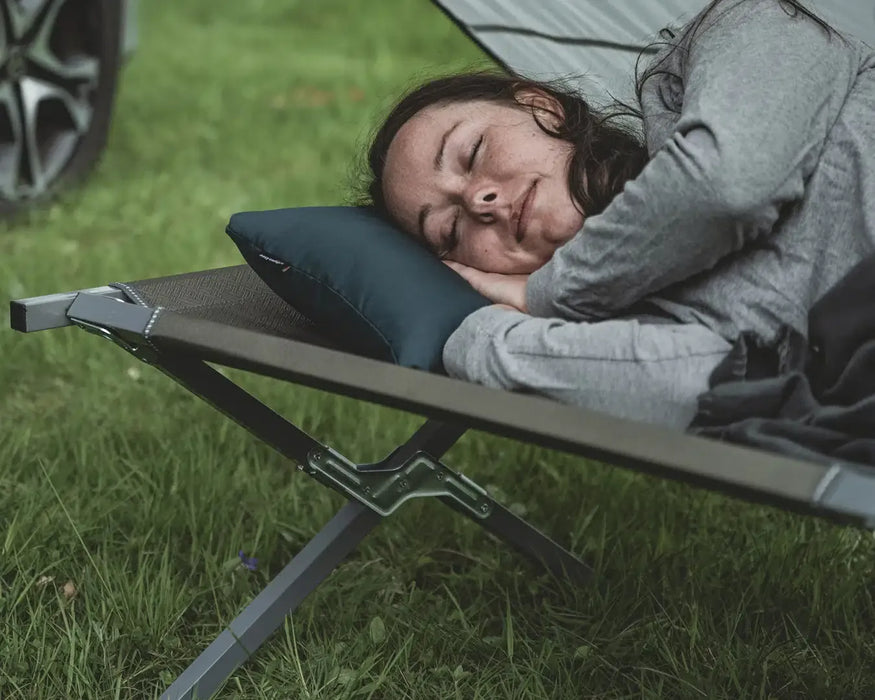 Easy Camp Raven Compact Camping Travel Pillow - lifestyle image, showing person lying on camp bed with pillow