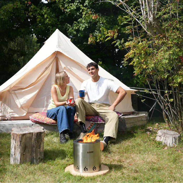 EcoFuego Fire Pit - lifestyle image with white tepee and two people enjoying a coffee