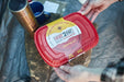 Heat 2 Eat, Medium Self Steamer Red 'Heat 2 Eat' self-steamer kit held by a person with outdoor items in the background