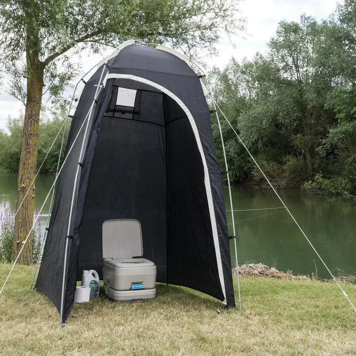 Kampa Loo-Loo Camping Toilet and Shower Tent - lifestyle image, showing tent with door open and camping toilet, chemical fluid and toilet roll inside, pitched  outside next to river and trees