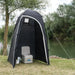Kampa Loo-Loo Camping Toilet and Shower Tent - lifestyle image, showing tent with door open and camping toilet, chemical fluid and toilet roll inside, pitched  outside next to river and trees