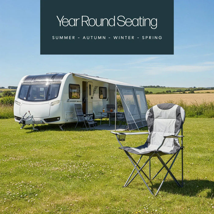 Leisurewize High Back Padded Folding Camping Chair with Cup Holder - lifestyle image, showing chair positioned on grass in field, with caravan and awning positioned behind to the left