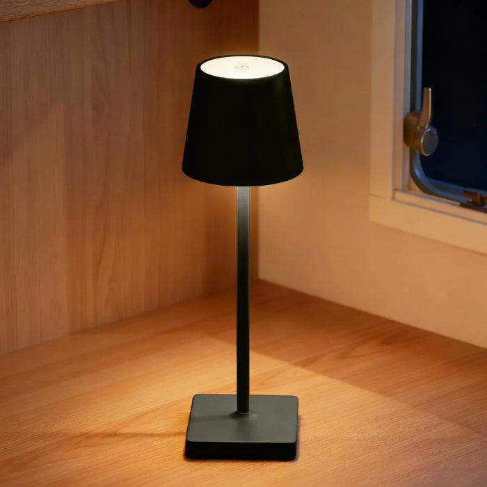 Leisurewize Lucia Rechargeable Table Lamp – Black - lifestyle image, showing lamp illuminated and sat on wooden worktop inside caravan