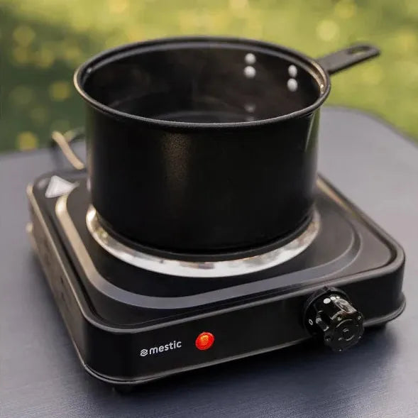 Mestic MKT-120 Single Electric Camping Hotplate - lifestyle image, showing the hotplate being used outdoors to heat a saucepan