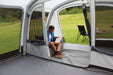 Outdoor Revolution Airedale 6S Inflatable Tent 2024 - 6 Berth Tunnel Tent feature image of tent pitched on campsite. view from inside may living area with dividing door in centre unzipped and man sat to left in inflatable chair, front left side of door unzipped. All curtains rolled up. 