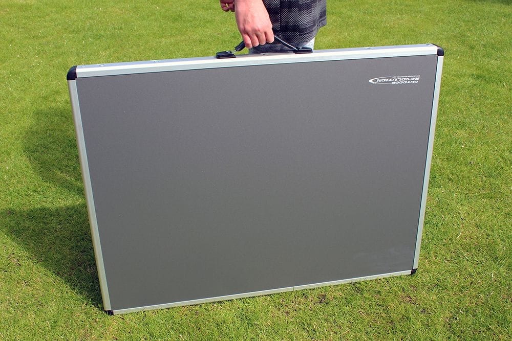 Grey folding table with carrying handle on a grassy background