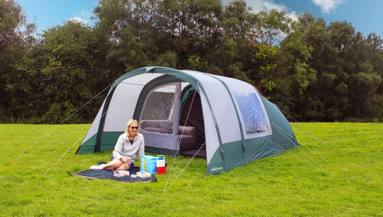 Outdoor Revolution Atom 500 - lifestyle image, showing person sat on picnic blanket in front of tent, pitched in field surrounded by trees, with furniture inside