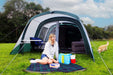 Outdoor Revolution Atom 500 - lifestyle image, showing person sat on picnic blanket in front of tent with furniture inside, and dog to right-hand side of frame