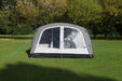 Outdoor Revolution Camp Star 600 PC DT- Polycotton Poled 6-Berth Tunnel Tent Bundle image of the tent pitched on a campsite surrounded by green trees. front view image with door zipped shut and both window panels without curtains