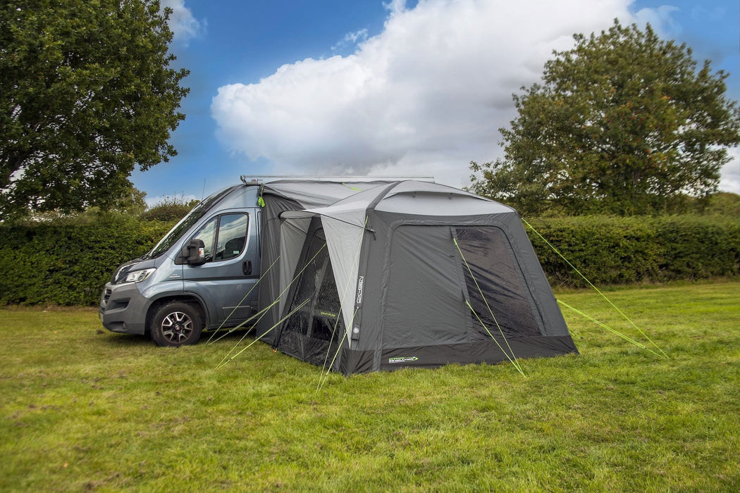 orda1623-10 Van with an attached caravan awning in a grassy area with trees and blue sky.