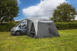orda1623-10 Van with an attached caravan awning in a grassy area with trees and blue sky.