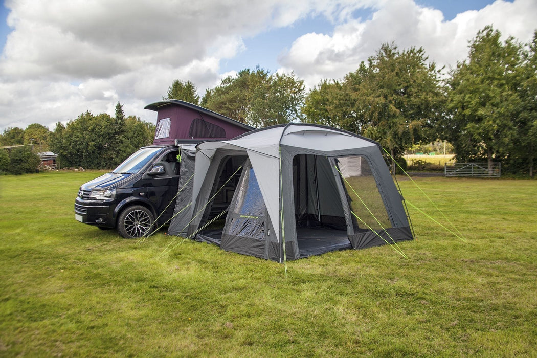 orda1640 Outdoor Revolution Cayman DT Awning attached to van with a large in a grassy field with trees in the background