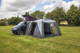 orda1640 Outdoor Revolution Cayman DT Awning attached to van with a large in a grassy field with trees in the background