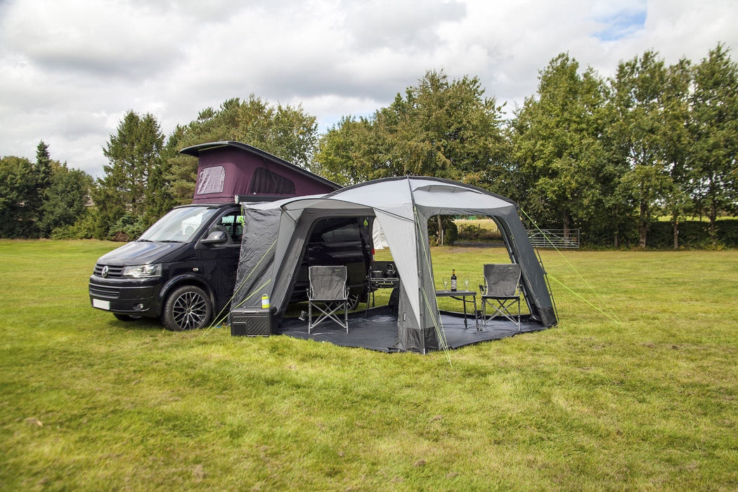 orda1640 Outdoor Revolution Cayman DT Awning attached to van with a large in a grassy field with trees in the background