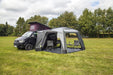 orda1640 Outdoor Revolution Cayman DT Awning attached to van with a large in a grassy field with trees in the background