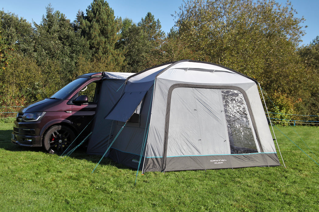 Outdoor Revolution Cuda (F/G) Low Drive Away Awning Feature image of the awning pitched on campsite grass with green trees surrounding. pitched against vw van with left side view showing front of van and awning front and left side