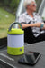Outdoor Revolution Lumi-Mosi Recharageable Lantern & Mosquito Killer - lifestyle image, showing unlit lantern, without mosi-killer compartment extended, sat on table outside next to smart phone, with person sat in background