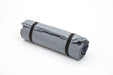 A grey rolled-up sleeping pad or mat secured with two black straps, photographed on a clean white background.