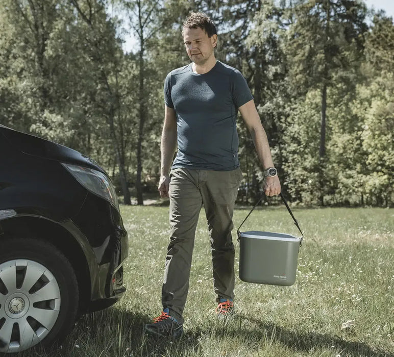 Outwell Arctic Poppy 14 Litre Camping Coolbox - lifestyle image, showing person carrying coolbox by carry strap