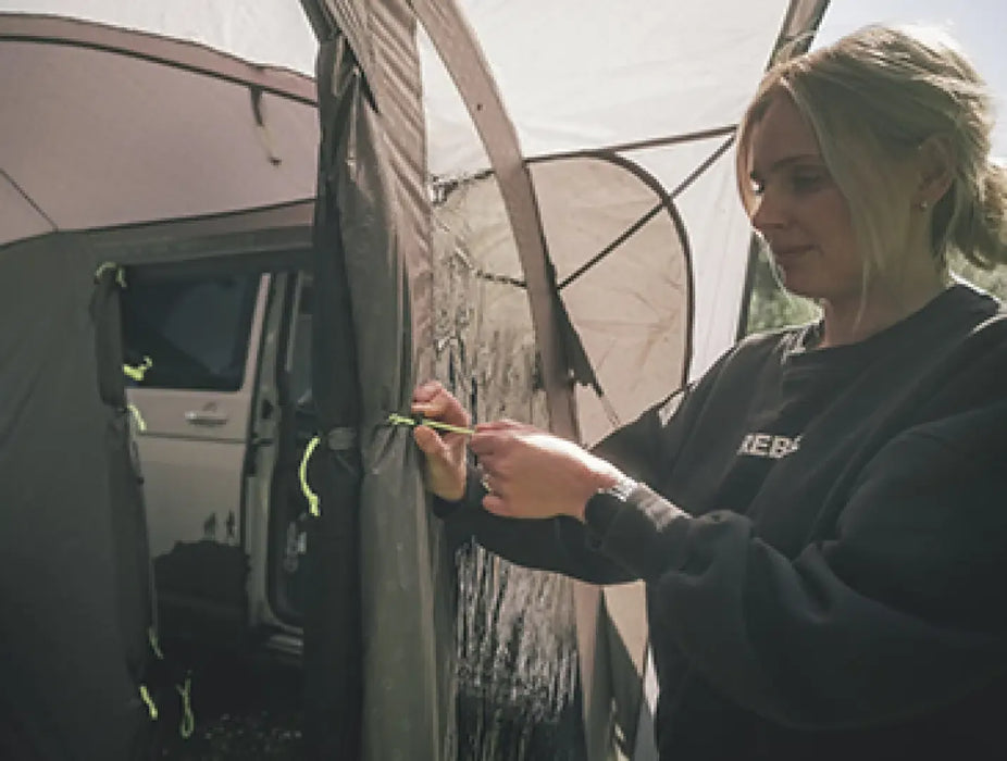 Outwell Armona Campervan Drive Away Awning - lifestyle image, showing person using toggle system