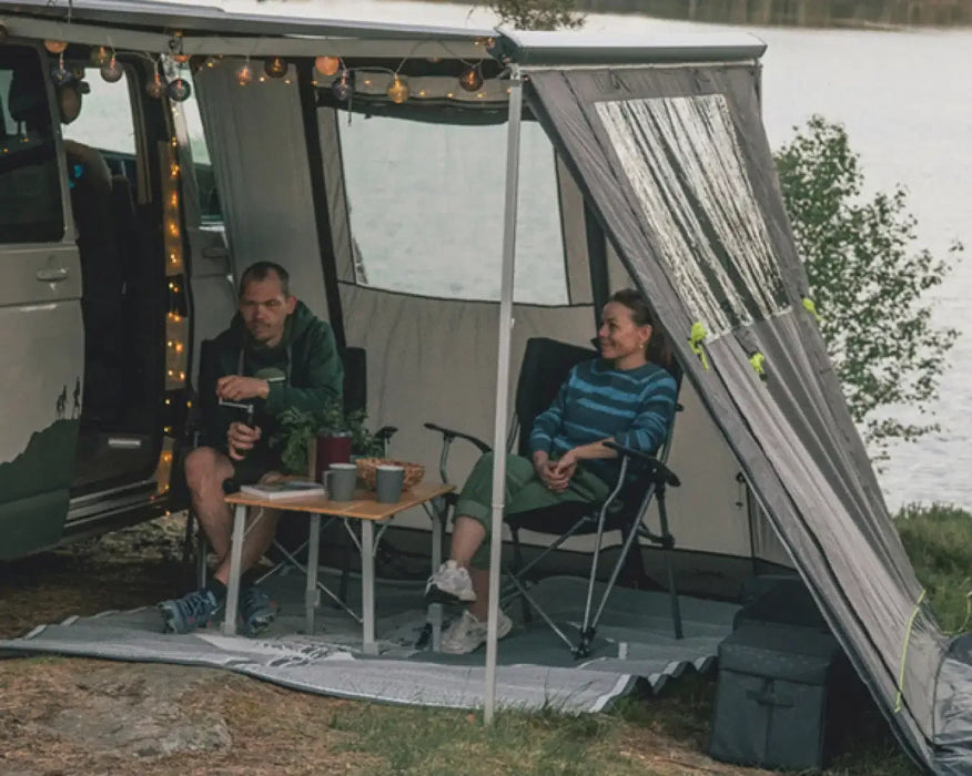 Outwell Backroads Campervan Awning Room - lifestyle image, showing annexe attached to vehicle with side panel open, with couple sitting inside