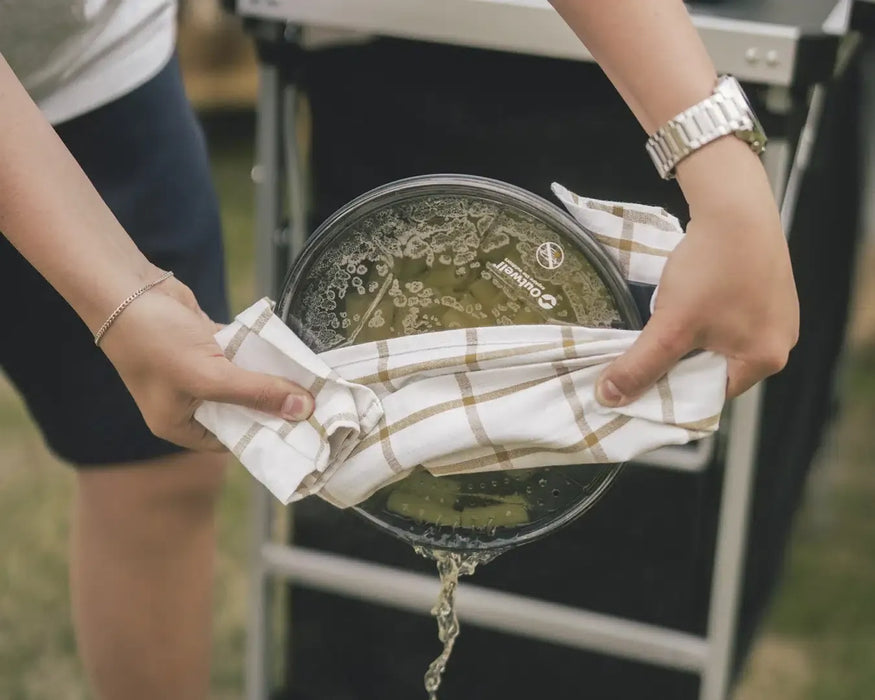 Outwell Collaps Stew Pot 2.5 Litre Camping Cooking Pot - lifestyle image, showing person draining water from cooking pot