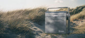 Outwell ECOcool 24L Cool Box 12V/230V – Slate Grey - lifestyle image, showing product outdoors on sand dune