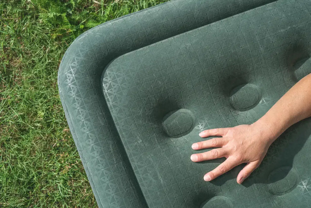 Outwell Flock Excellent King Size Inflatable Camping Mattress - lifestyle image, showing mattress outside on grass with person's hand in frame