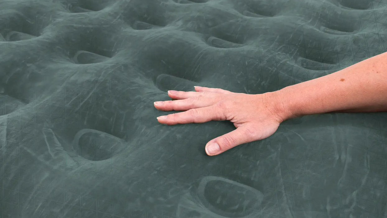 Outwell Flock Excellent King Size Inflatable Camping Mattress - product image, showing close-up of mattress upper material with person's hand