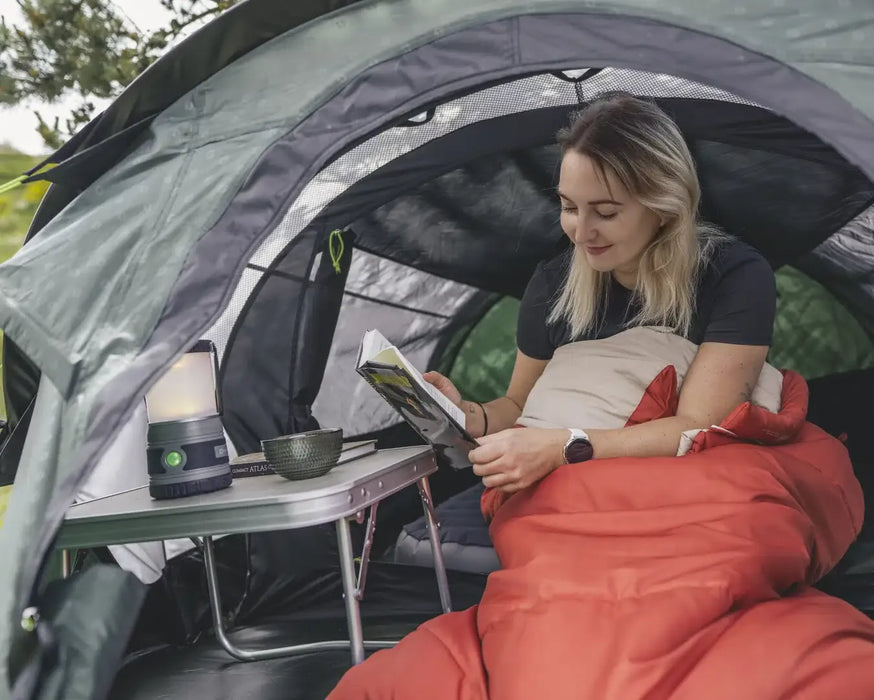 Outwell Nexion 2 - Instant Pitch 2-Person Pop-Up Tent - lifestyle image, showing woman sat up in sleeping bag reading a book