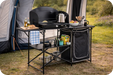 Quest Oregano Folding Camping Kitchen Stand with Storage – lifestyle image, showing unit being used in outdoor environment with awning behind