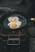 Robens Tahoe Pan feature lifestyle image of pan on outdoor stove with 2 eggs
