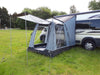 Sunncamp Motor Lodge 200 Drive Away Awning feature image of awning on motorhome with front canopy open with canopy poles holding it up. Both windows are exposed, awning pitched in field with tress in background