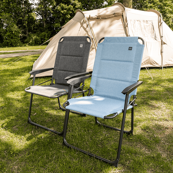Travellife Lago Compact Camping Chair Wave Blue - lifestyle image, showing two chairs (one grey, one blue) outside on grass with tent in the background