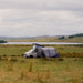 Vango Cove III Air Inflatable Drive Away Awning Smoke Grey - Low lifestyle image of the awning in field attached to  pop top van with lake behind and mountains in the distance