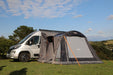 Vango Kela Pro Air Drive Away Awning - Mid lifestyle image of awning pitch against motorhome in filed with all doors zipped up and closed and curtains up. view shows left side. 