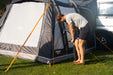 Vango Kela Pro Air Drive Away Awning - Mid lifestyle image of the awning pitched against motorhome. Father and Daughter pumping up airbeam. all doors full zipped up