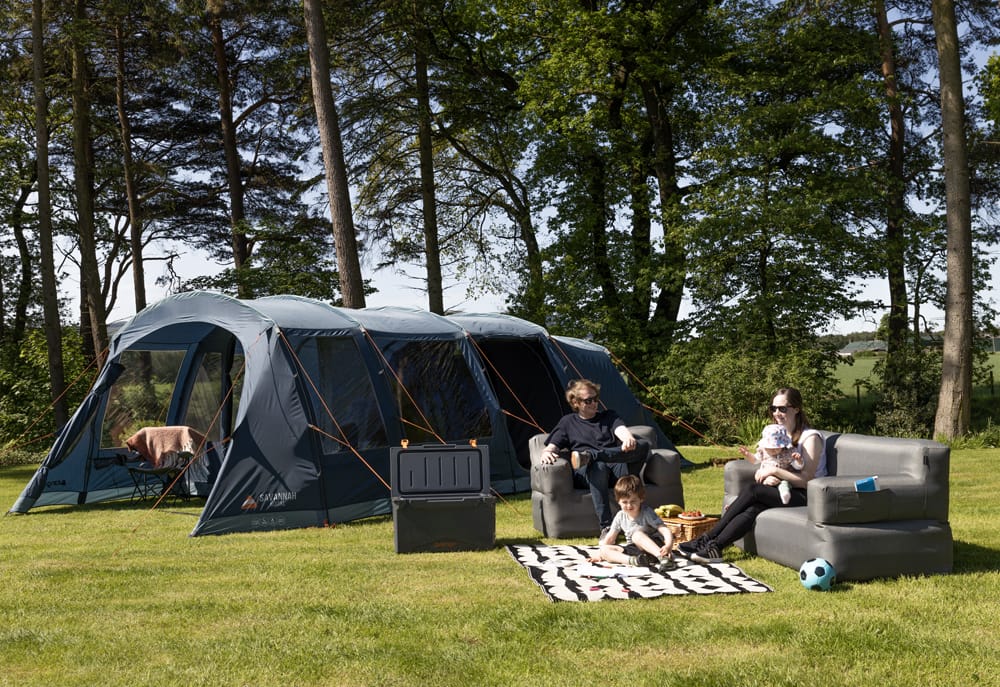 Vango Savannah 600XL 6-Person Family Tent Package - lifestyle image, showing family sat on inflatable furniture in front of pitched tent